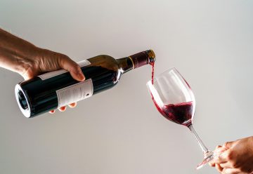 une personne versant un verre de vin dans la main d’une autre personne