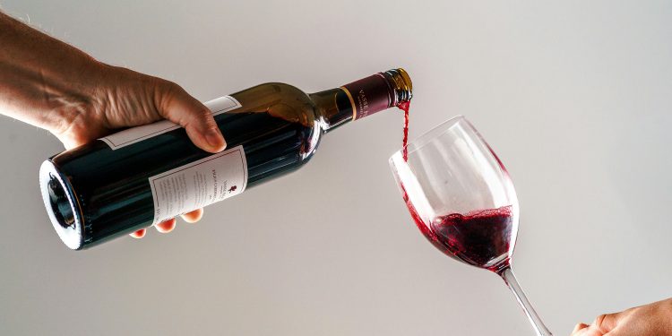 une personne versant un verre de vin dans la main d’une autre personne