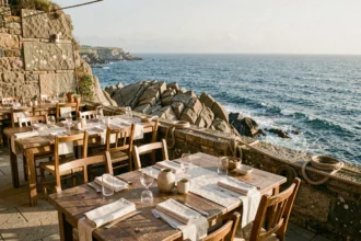 Terrasse de restaurant bretonne avec vue sur la mer, tables en bois dressées face à l'Atlantique sous un ciel bleu
